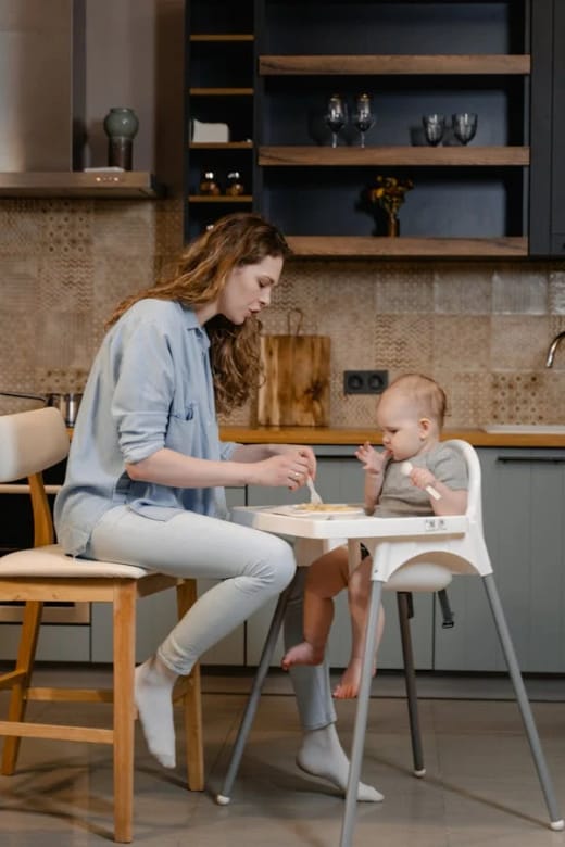 A parent sharing a mealtime with their young child in a kitchen