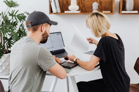 Two colleagues collaborating over a laptop at a desk