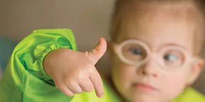 A young child wearing glasses playing and learning