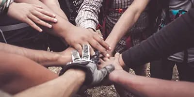 A group of hands joined together in the centre of a circle